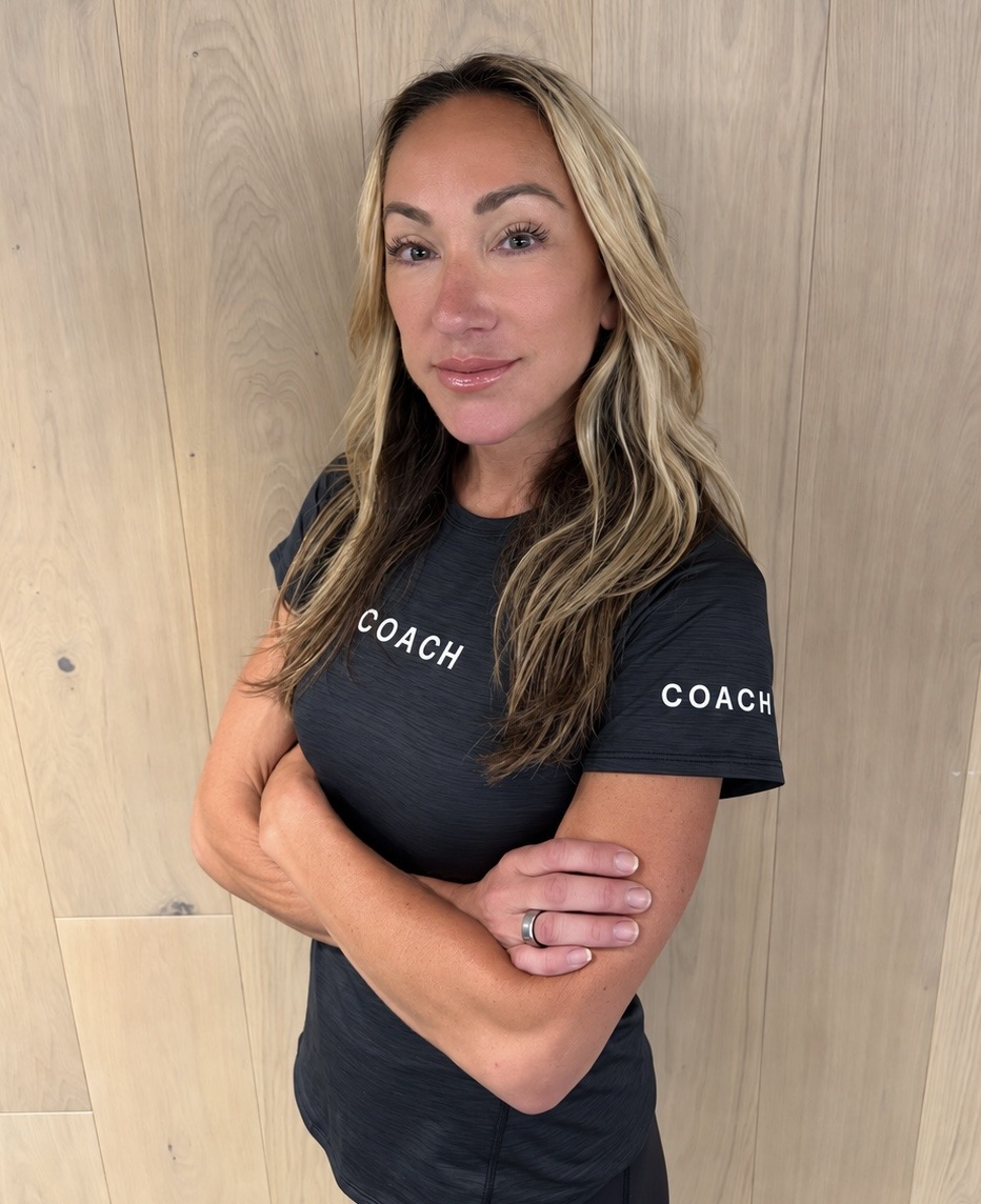 Coach Sarah Haskell standing with arms crossed in a COACH shirt